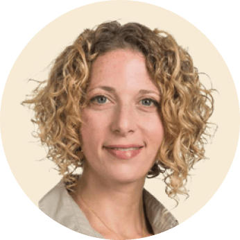 female with curly hair smiling in a round frame, professional headshot with neutral background