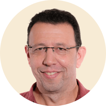 headshot of a middle-aged man with glasses on a light background, smiling man in a maroon shirt with dark hair