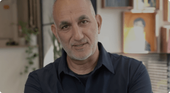man in navy shirt smiling, modern workspace with art in background